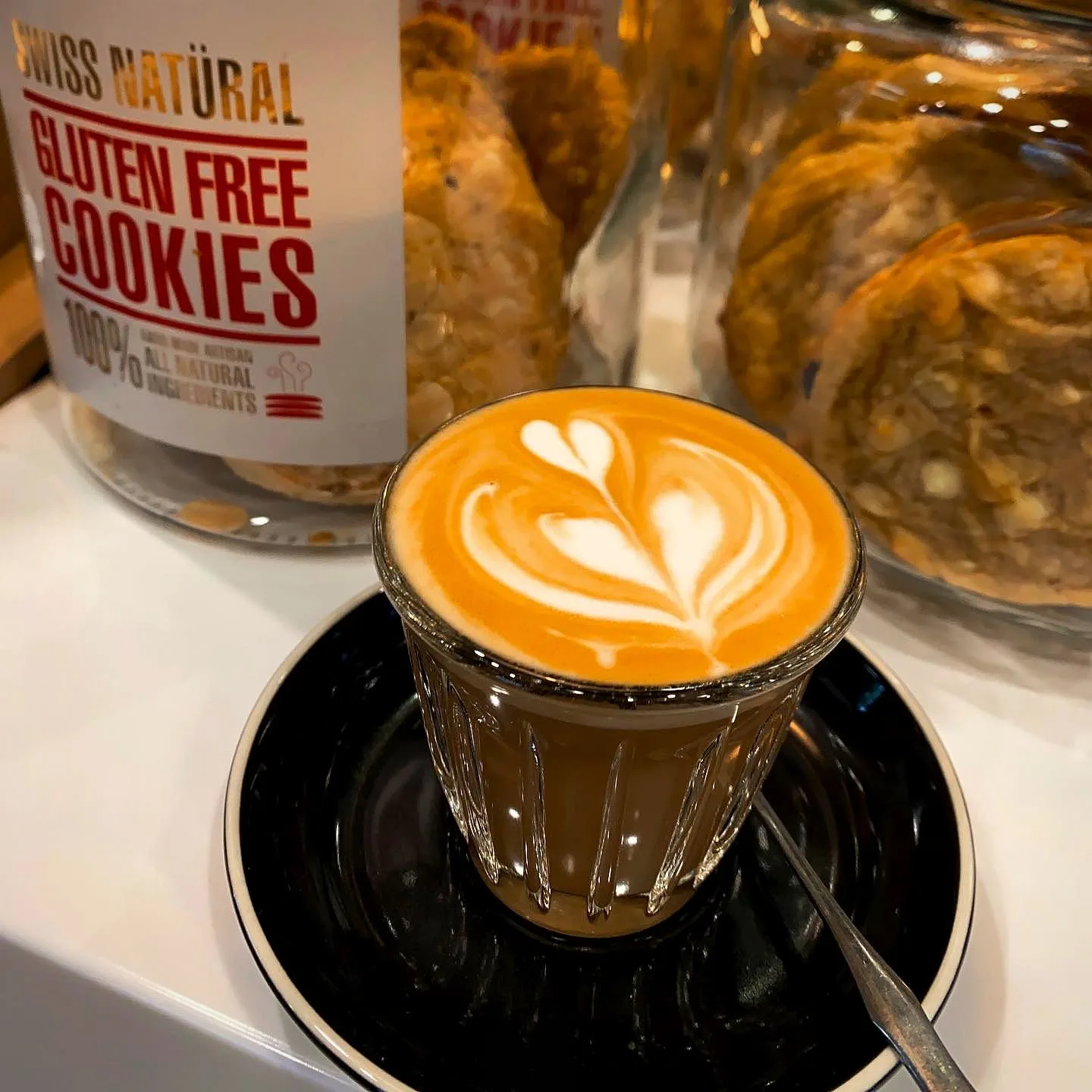 Gluten free cookies jar next to a flat white